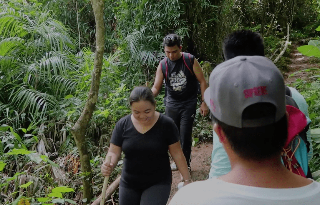 hikers with sticks on a trail in a forest coming back the point binurong natural landmark in catanduanes philippines